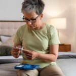 Diabetes: What It Is, Causes, Symptoms Woman preparing an insulin injection for diabetes management at home.