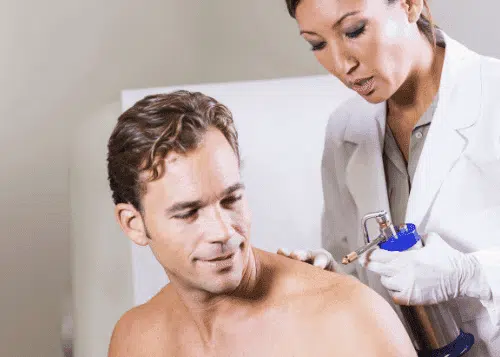 Man receiving cryotherapy treatment from a healthcare professional.